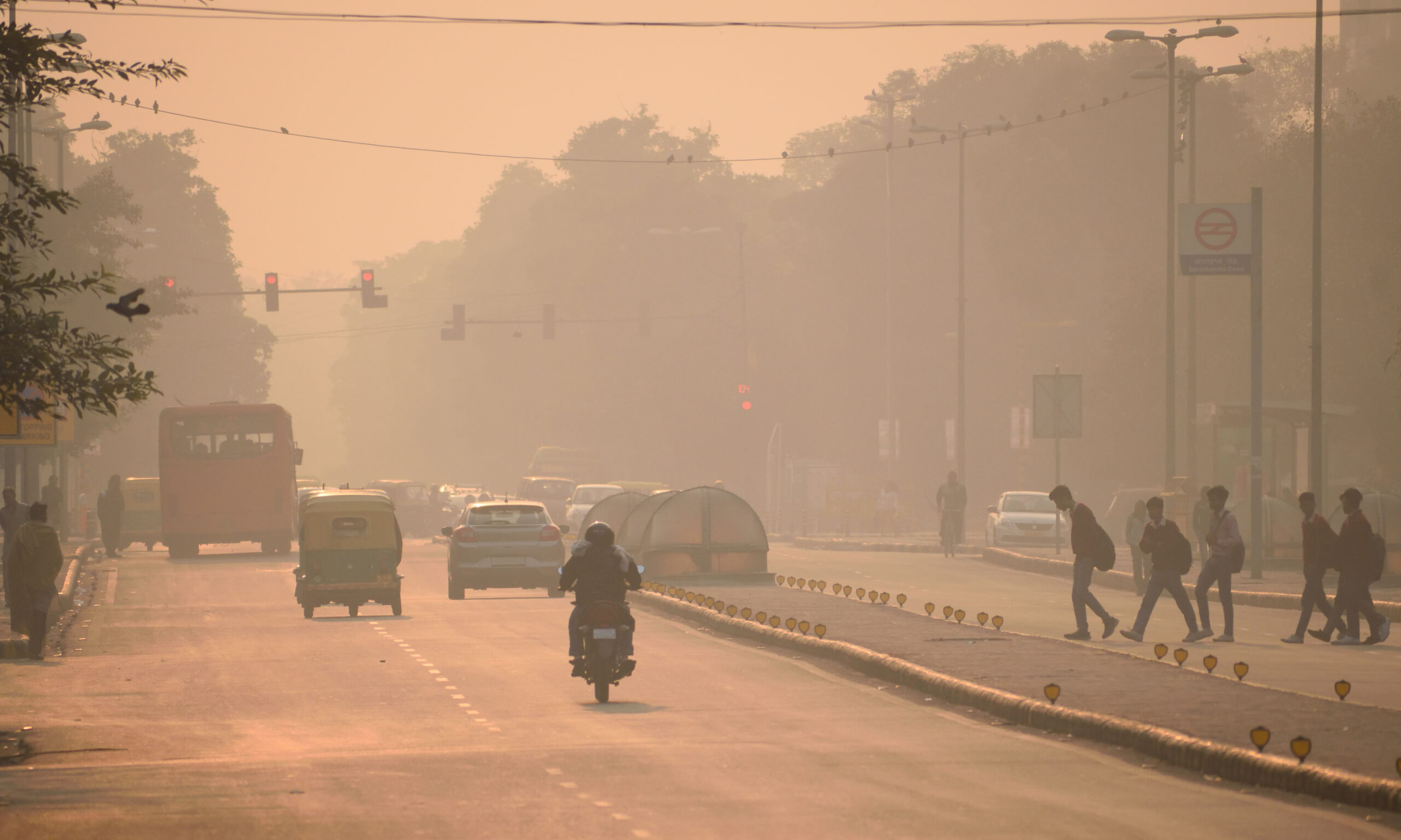 Vehicles and people moving in the streets amidst heavy smog