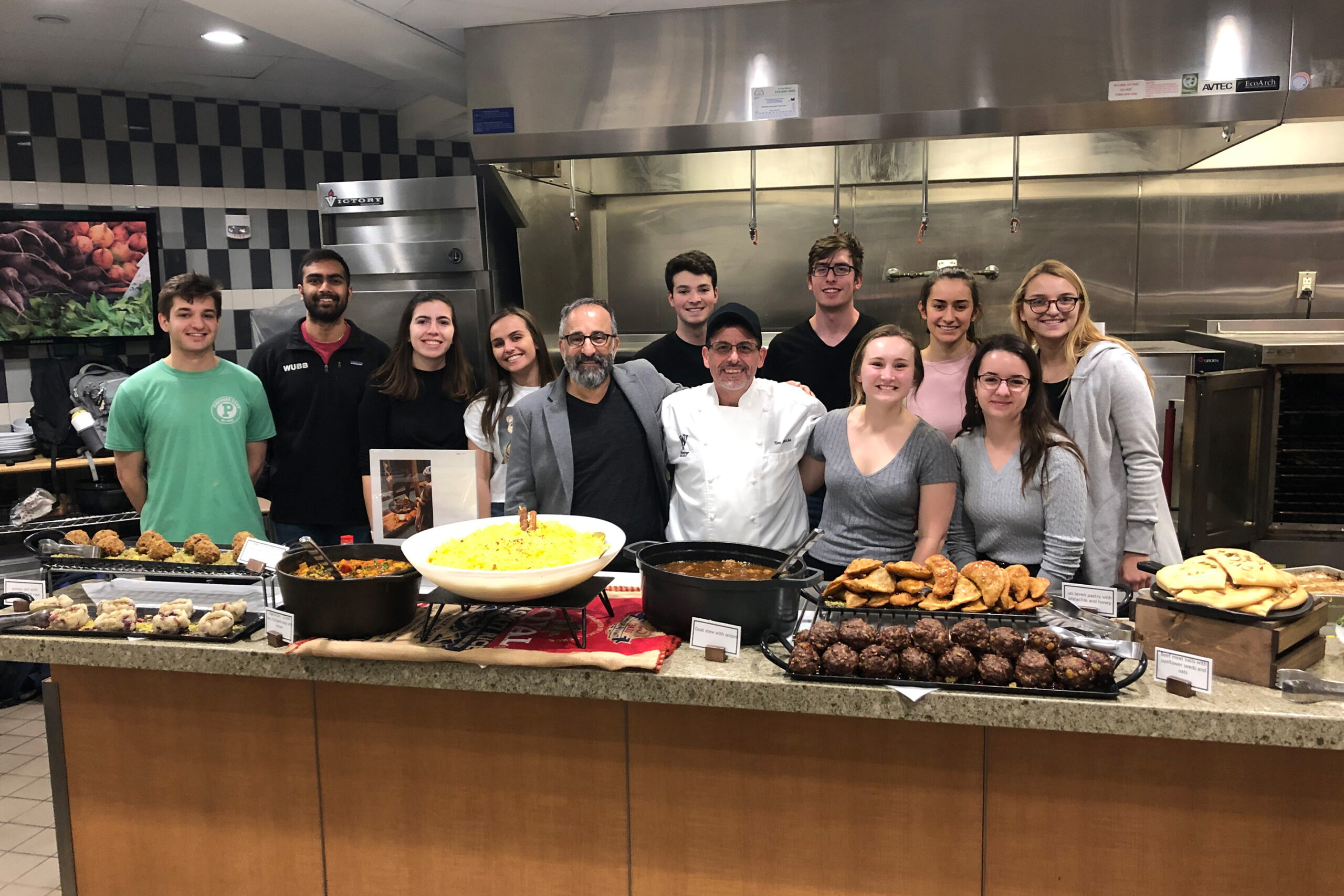 Professor Hayrettin Yücesoy, in gray jacket at center, surrounded by his students in a kitchen