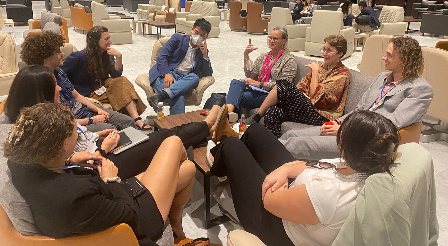 Students and professors sit in a circle and discuss the conference