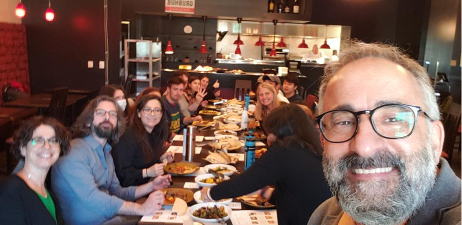 Hayrettin Yucesoy poses for a selfie with students at a long dinner table