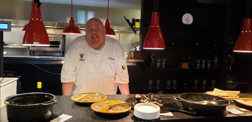 Chef Patrick Tague stands in front of kitchen